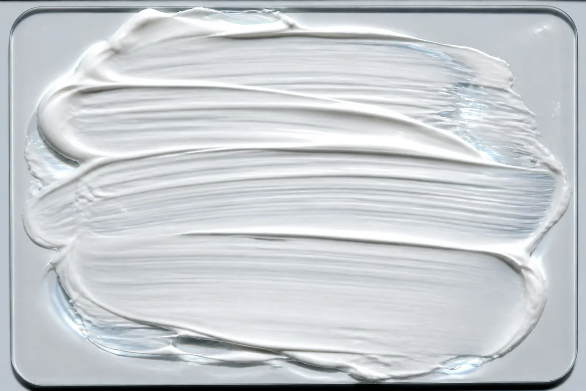 Texture de crème solaire blanche étalée en couche fine sur une plaque de verre